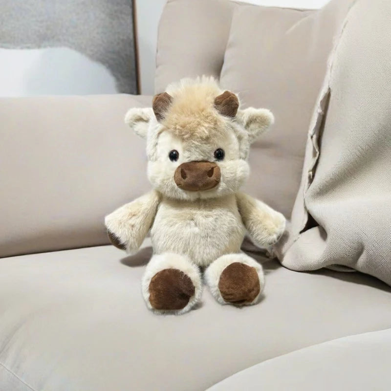 Toffee the Oat Highland cow plush sitting on a sofa